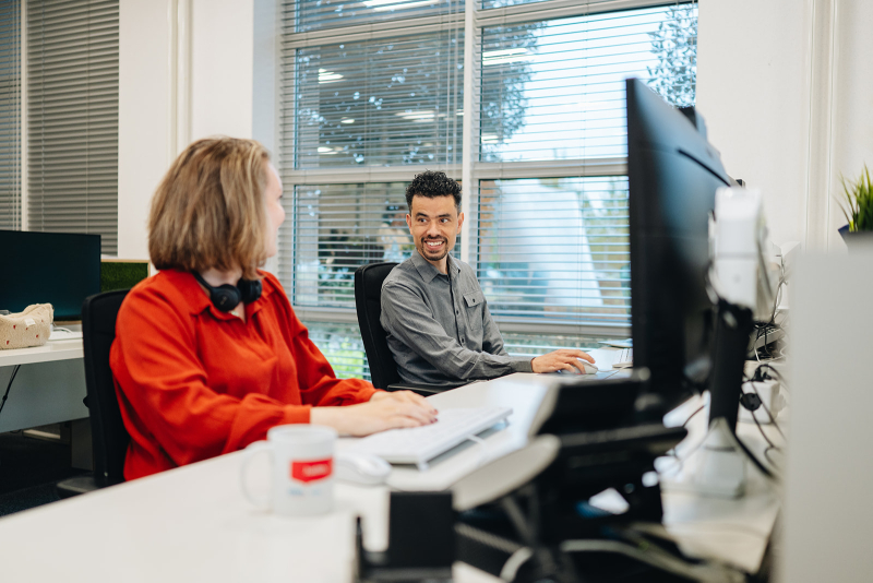 Twee medewerkers achter bureau