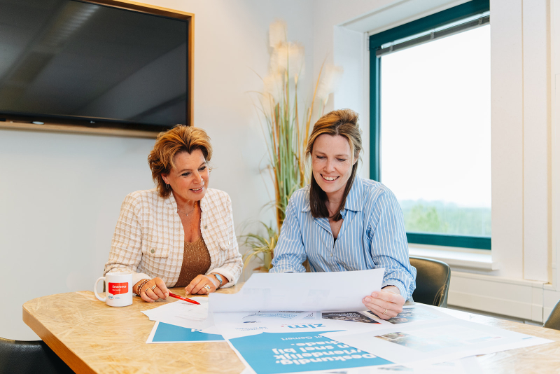 Twee medewerkers aan tafel beoordelen poster