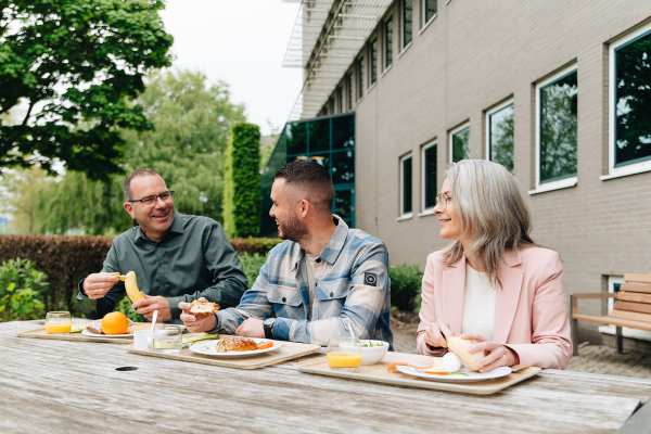 Drie collega's buiten aan het lunchen