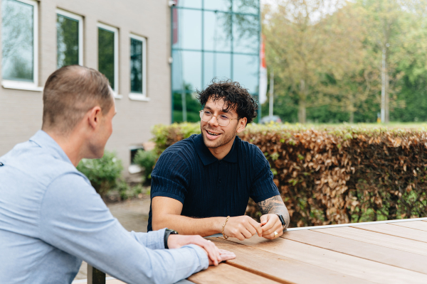 Twee medewerkers aan buitentafel in gesprek