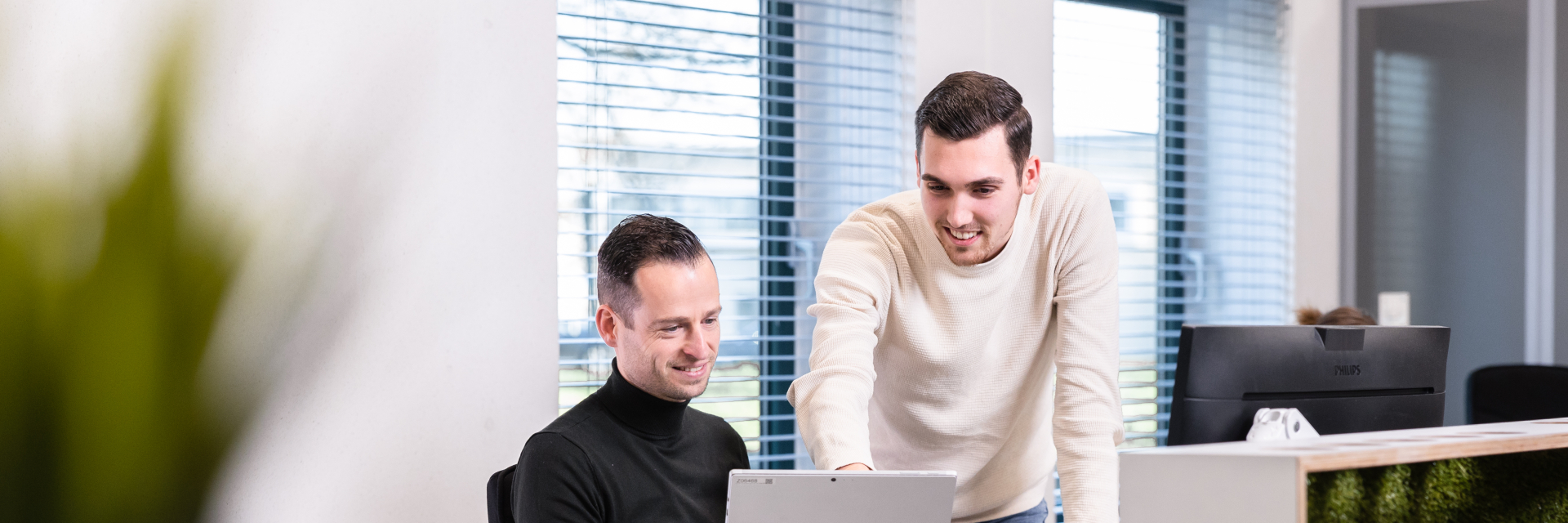 Twee mannelijke medewerkers aan bureau met tablet