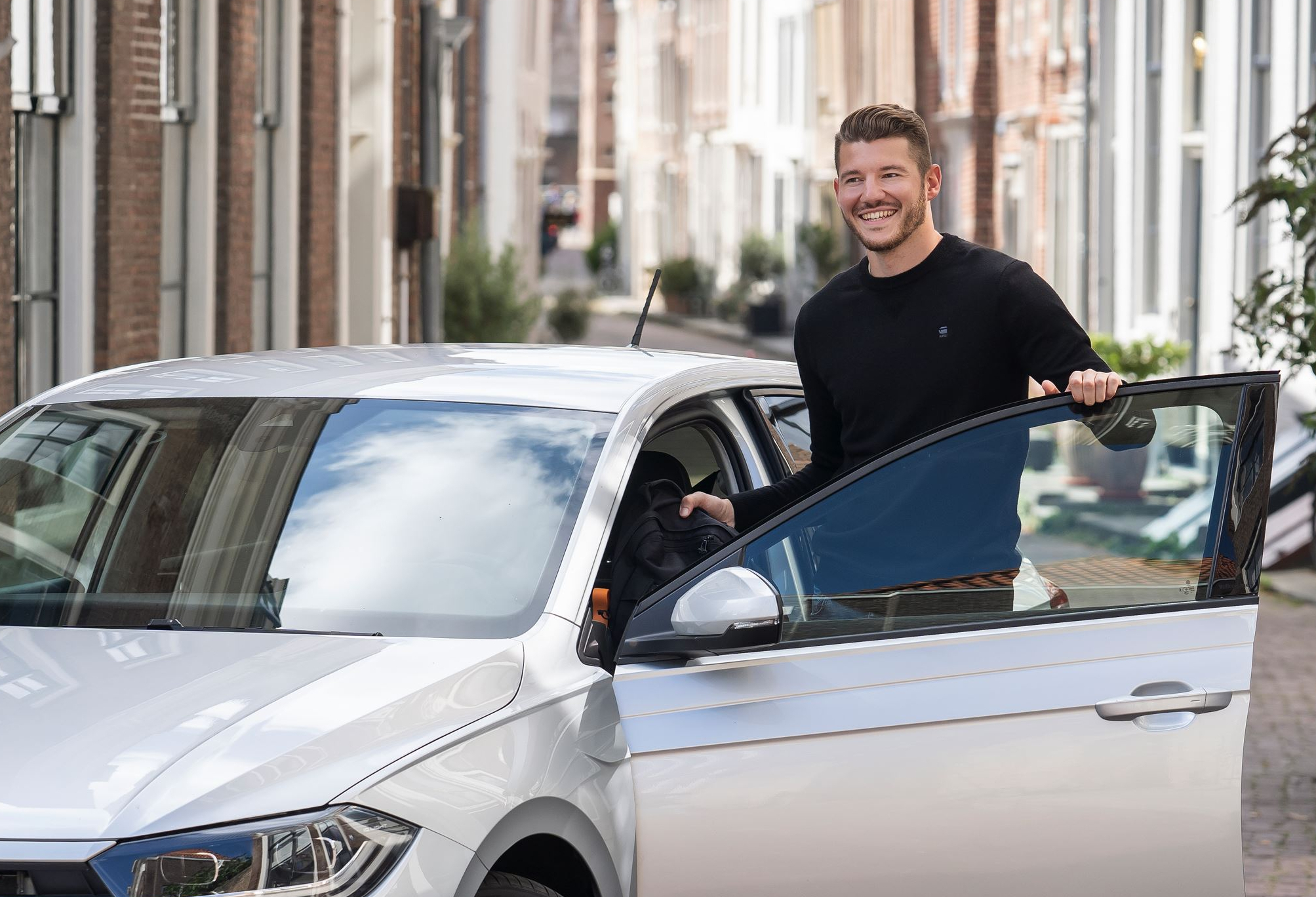 Man bij auto met open portier